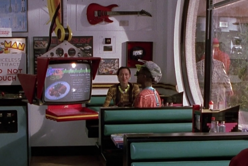 <p><strong>Figure 1.2</strong> Once inside, he is confronted with a strange scene — a mix of 1980s nostalgia and futuristic technology. A prime example is the robotic waitstaff he encounters, which feature the logo on their menu screens.</p>