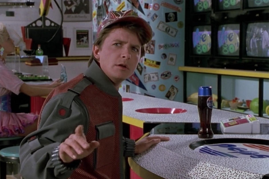 <p><strong>Figure 1.4</strong> As Marty makes the connection between old Biff and Griff, we see the Cafe 80s logo on video screens in the background. The logo pops in like a commercial between 80s TV show segments.</p>