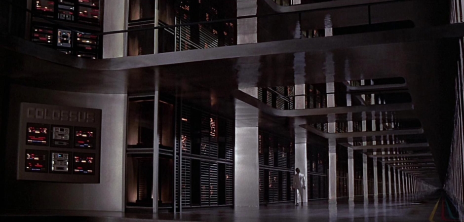<p><strong>Figure 1.1</strong> The film opens with Dr. Charles Forbin walking the halls of a massive supercomputer complex, activating an artificial intelligence that will control the entirety of America’s nuclear defense from that point forward. On the far left, a logotype is rendered large across the top of a wall-mounted bank of control panels—it reads COLOSSUS.</p>