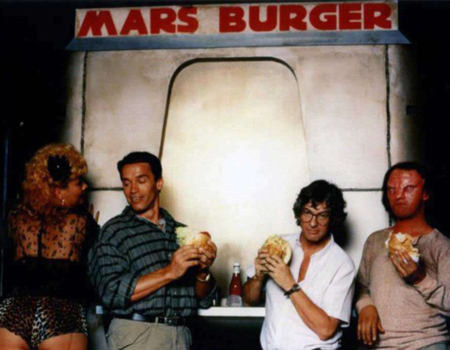 <p>Figure 1.2 The Mars Burger was used in behind the scenes photography, featuring actor Arnold Schwarzenegger (center-left) and director Paul Verhoeven (center-right). Source: <em>ScreenCrush News</em></p>