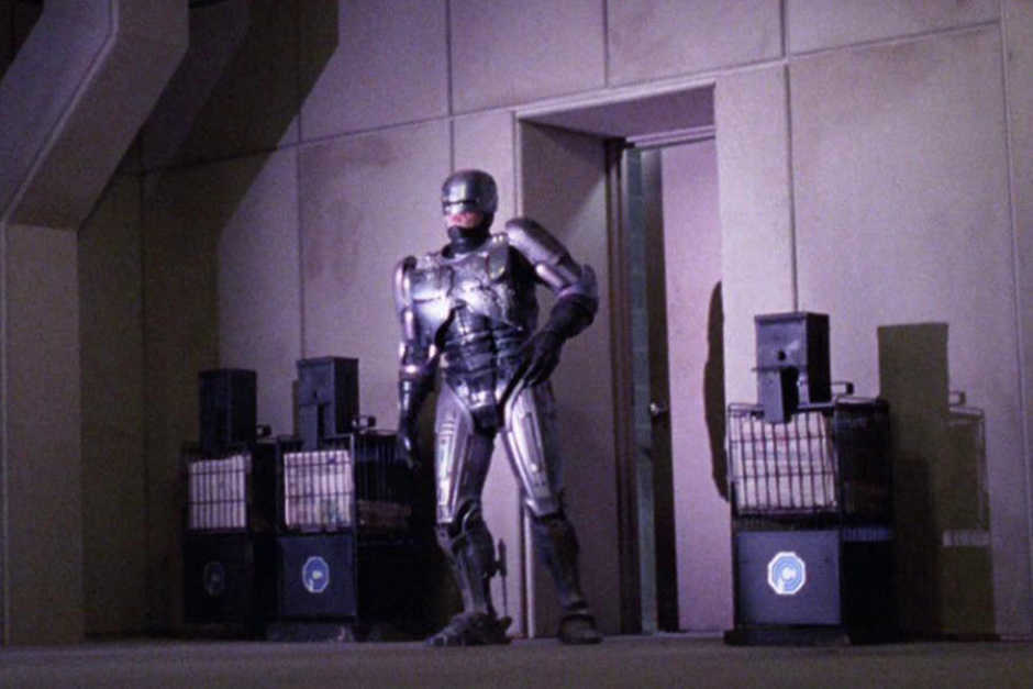 <p><strong>Figure 3.13</strong> As RoboCop exits the OCP corporate headquarters at the parking garage level, we see newspaper machines bearing the OCP mark.</p>