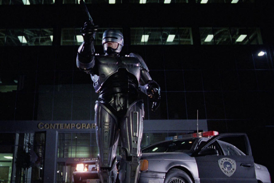 <p><strong>Figure 5.3</strong> RoboCop making an arrest, with the OCP Detroit Police shield in the background.</p>
