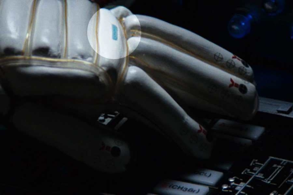 <p><strong>Figure 2.11</strong> As Ripley operates shuttle controls to drive the alien into her trap, we see the logo (highlighted) on her space suit gloves.</p>